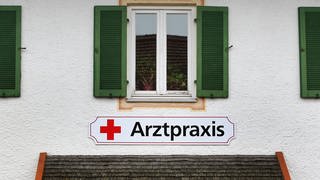 Schild "Arztpraxis" an einer Hauswand