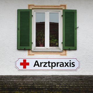 Schild "Arztpraxis" an einer Hauswand
