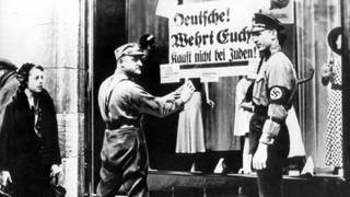 SA-Männer kleben während des Dritten Reiches ein volksverhetzendes Plakat mit der Aufschrift "Deutsche! Wehrt Euch! Kauft nicht bei Juden" an der Schaufensterscheibe eines Geschäfts (undatiertes Archivfoto).
