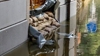 Sandsäcke vor einem Hauseingang in einer überfluteten Straße