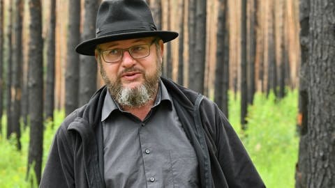 Biologe und Professor für nachhaltige Entwicklung,Pierre Ibisch, in einem Wald, der sich von einem Feuer erholt.