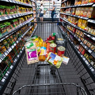 Ein Einkaufswagen in einem Supermarkt, der mit Lebensmittel gefüllt ist.