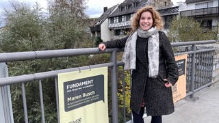 Maren Busch steht auf der alten Lahnbrücke in Diez neben einem ihrer Wahlplakate.