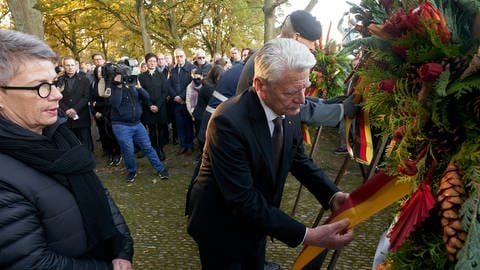 Bundespräsident a.D. Joachim Gauck und Bettina Hörter, Geschäftsführerin des Volksbunds Kriegsgräberfürsorge Koblenz-Trier, legen bei einer Veranstaltung zum Volkstrauertag auf dem Soldatenfriedhof in Sinzig Kränze nieder.