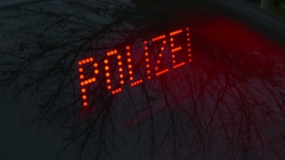In roten Leuchtbuchstaben steht das Wort Polizei vor dunklem Hintergrund geschrieben