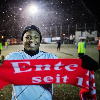 Ein junger Mann hält in Mainz  einen "Enten-Schal" in den Händen. Der Fußballverein "FC Ente Bagdad" versucht, durch Sport junge Flüchtlinge in Deutschland zu integrieren und wurde dafür jetzt mit dem Brückenpreis des Landes Rheinland-Pfalz ausgezeichnet.