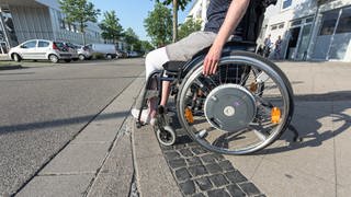 Rollstuhlfahrerin hält am Straßenrand