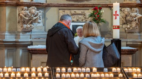 Besucher stehen im Trierer Dom vor einem Bild des an Silvester verstorbenen, emeritierten Papstes Benedikt XVI.