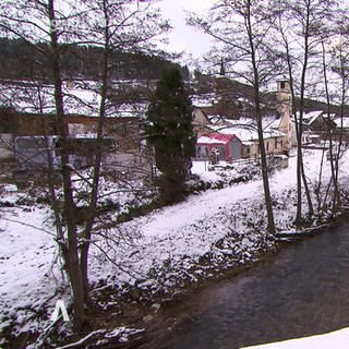 Ein Bach durchquert ein verschneites Dorf