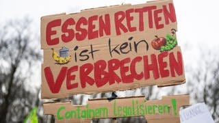 Plakat bei einer Demonstration mit der Aufschrift «Essen retten ist kein Verbrechen - Containern legalisieren!».