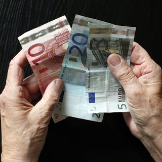 Hände einer alten Person halten Geldscheine
