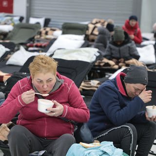 Flüchtlinge essen in einer Notunterkunft.