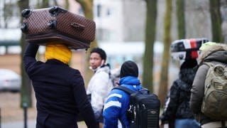 Flüchtlinge tragen ihre Koffer auf dem Kopf während sie ins Ankunftszentrum Reinickendorf gehen. 