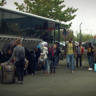 Geflüchtete Menschen steigen aus Bus aus