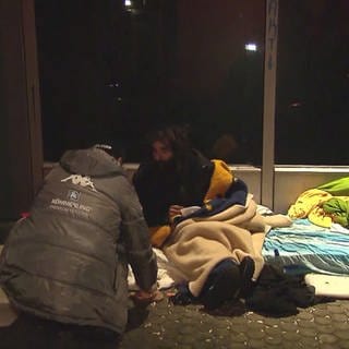 ein Sozialarbeiter unterhält sich mit einem Obdachlosen