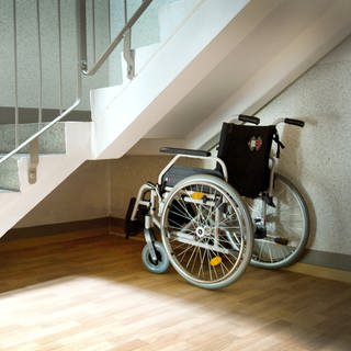 Ein Rollstuhl steht unter einer Treppe
