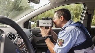 Polizist im Auto mit Radarfalle