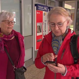 Zwei Damen mit Smartphone am Bahnhof