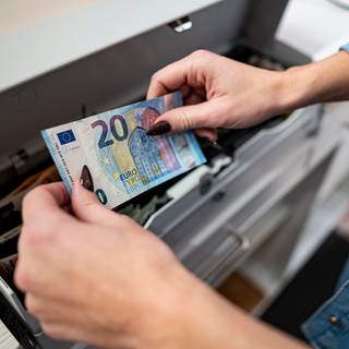 Eine Mitarbeiterin legt Geld in die Kasse eines Modeladens.