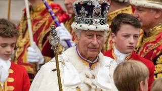 Großbritanniens König Charles III. verlässt nach der Krönungszeremonie mit der Imperial State Crown, einem Zepter und dem Reichsapfel die Westminster Abbey. 
