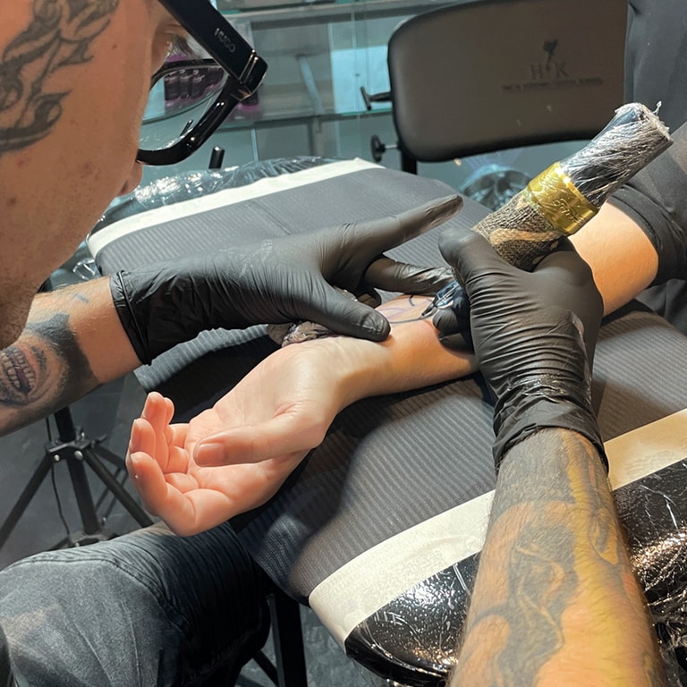 Ein Tattoo-Artist sticht seiner Kundin das Organspendetattoo.