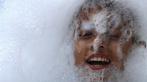 Ein Junge spielt mit Schaum in einer Badewanne.