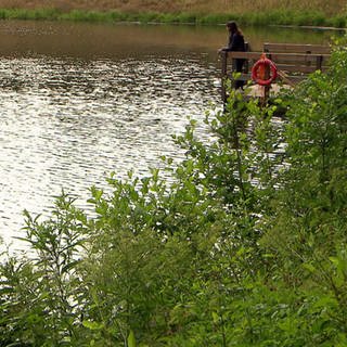 Frau steht an einem Teich