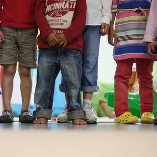 Mehrere Kinder stehen in einem Kindergarten nebeneinander