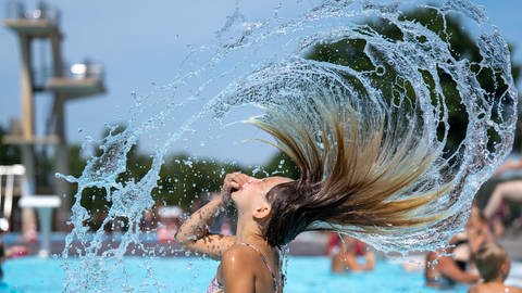Ein Mädchen verschafft sich Abkühlung in einem Freibad, am Wochenende wird es in RLP bis zu 36 Grad warm