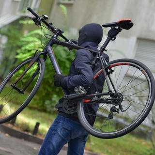 Ein Dieb trägt ein Fahrrad weg