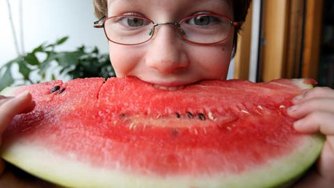 Die neunjährige Ruby beißt in eine Wassermelone.