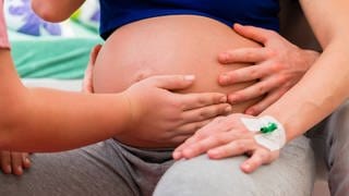 Eine schwangere Frau sitzt bei einer medizinischen Behandlung.