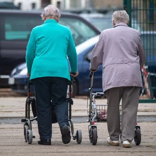Seniorinnen gehen mit ihrem Rollator durch die Stadt. 