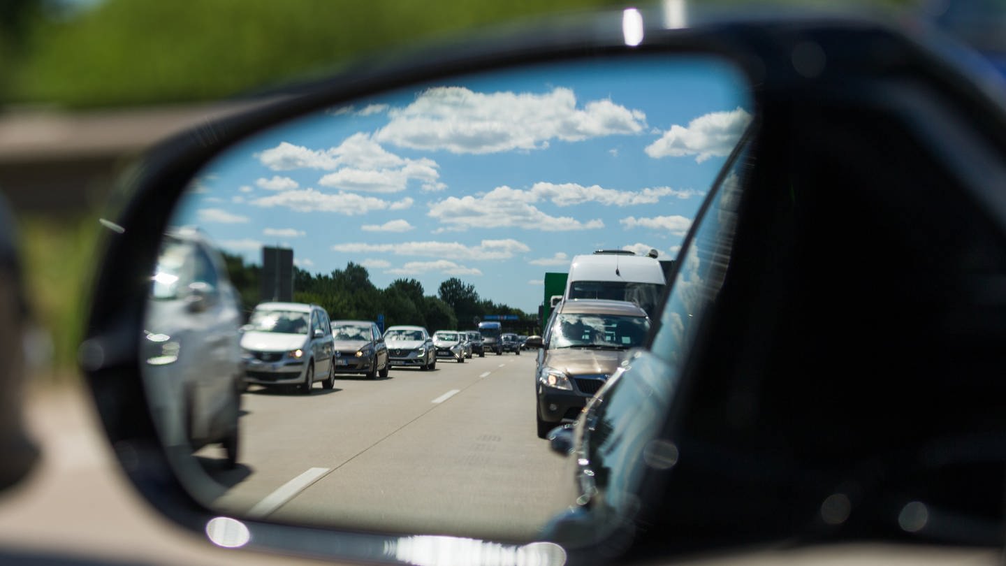 Außenspiegel eines Autos zeigt zähfließenden Verkehr auf der Autobahn