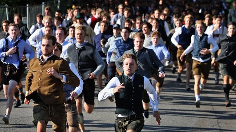 Oktoberfestbesucher stürmen nach der Eröffnung des Platzes auf die Festwiese.