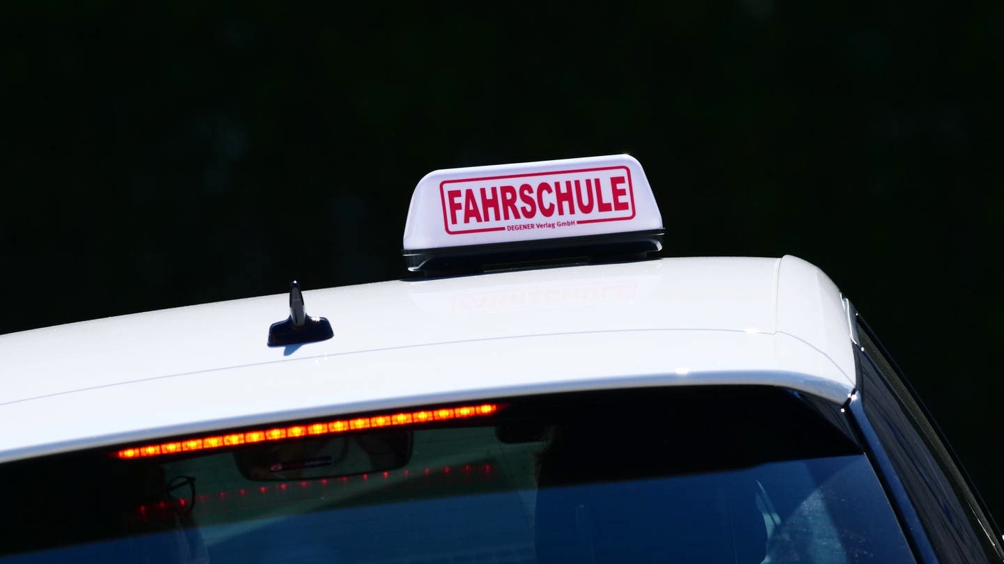 Ein weißes Auto mit einem Schild auf dem das Wort Fahrschule steht.