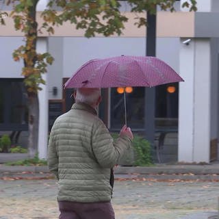 Mann mit Regenschirm unterwegs in Ludwigshafen