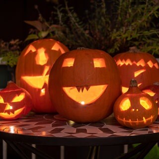 An Halloween stehen geschnitzte Kürbisse auf einem Tisch.