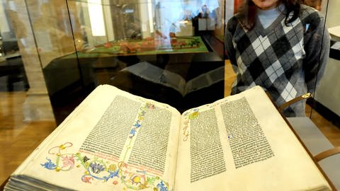 Eine Frau betrachtet das Ausstellungsstück die "Gutenberg-Bibel".
