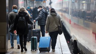 Reisende am Bahnhof laufen mit Koffern zu einem Zug 