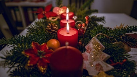 Adventsgesteck mit brennenden Kerzen auf Tisch