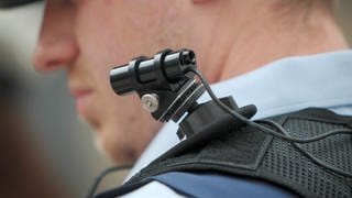 Ein Polizist trägt eine mobile Miniatur-Videokamera (Bodycam) auf seiner Schulter.