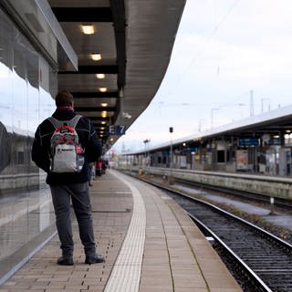 Pendler steht wegen des Bahnstreiks an einem leeren Gleis