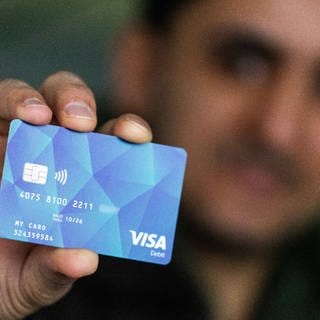 Ein Geflüchteter hält eine Debitcard in der Hand, die der Ortenaukreis als Bezahlkarte für Geflüchtete ausgibt.
