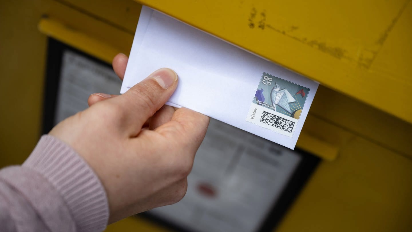 Ein Brief wird in einen Briefkasten eingeworfen. Bei der Briefzustellung gibt es oft Probleme und es dauert, bis Briefsendungen ankommen.
