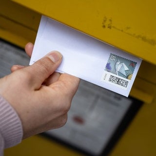 Ein Brief wird in einen Briefkasten eingeworfen. Bei der Briefzustellung gibt es oft Probleme und es dauert, bis Briefsendungen ankommen.