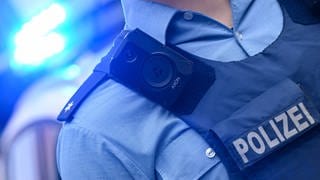 Ein rheinland-pfälzischer Polizeikommissar trägt eine Bodycam an seiner Schutzweste.