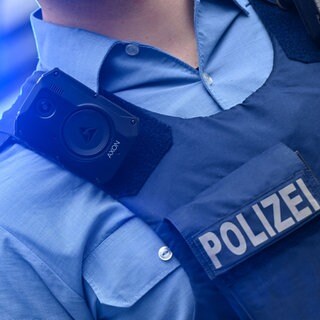 Ein rheinland-pfälzischer Polizeikommissar trägt eine Bodycam an seiner Schutzweste.