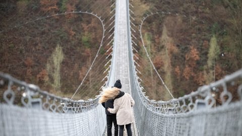 Ein Liebespaar steht auf der Hängeseilbrücke Geierlay