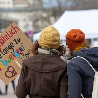 Zwei Frauen stehen mit einem Schild auf einer Großdemonstration gegen Rechtsextremismus.